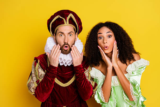 istock Couple dressed in elegant historical costumes sharing a surprise expression against a vibrant yellow background 2214826154