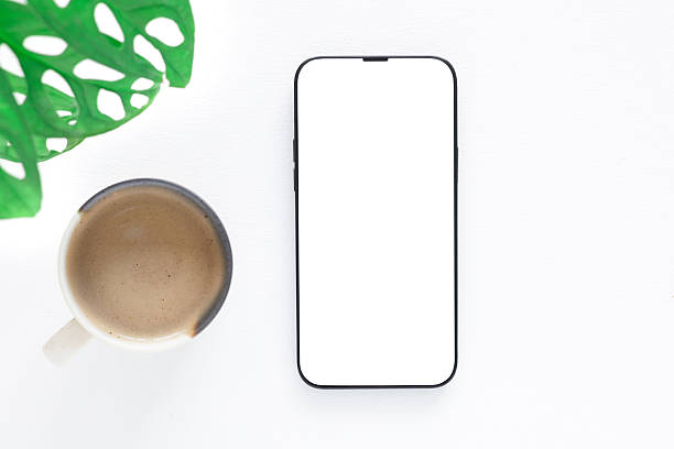 istock Top view, flat lay a modern smartphone with a blank white screen and coffee cup, plant over white background. 2214826179