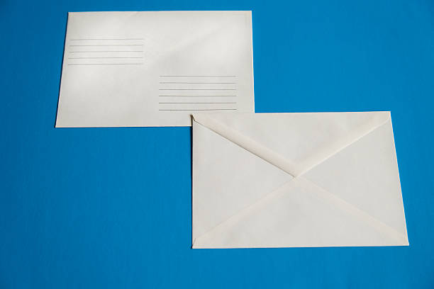 istock White mailing envelopes on a blue background. The blue color is associated with reliability and trust 2214826867