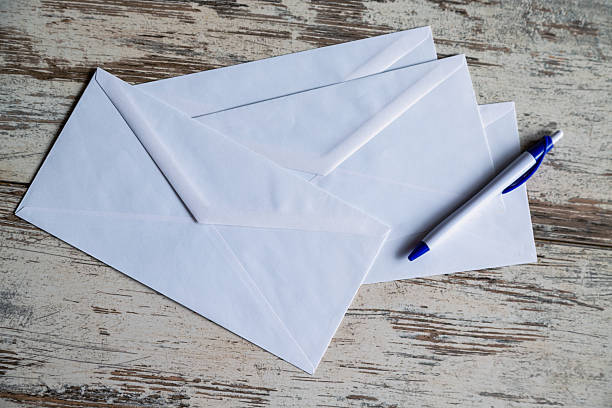 istock White mailing envelopes and a fountain pen on a wooden table reflect classic style and nostalgia for paper correspondence. For themes related to retro design, epistolary culture, and romantic letters. 2214826869