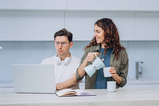 istock A woman pours coffee for her partner who is focused on work at the laptop, exemplifying a supportive dynamic in a home office setting 2214830497