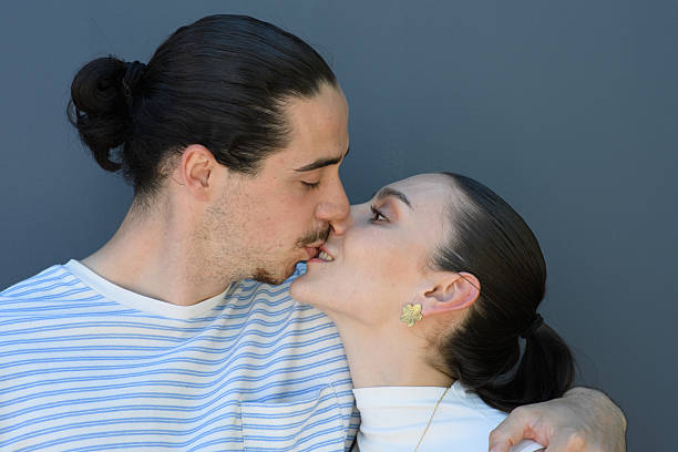 Two young lovers kiss each other on the mouth