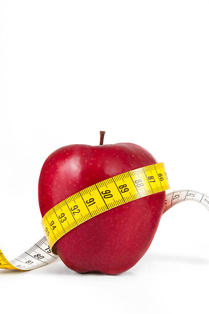 Diet concept with red apple and tape measure on white background
