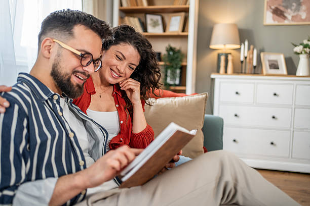 istock Happy couple reading a book together at home on the sofa 2214838085