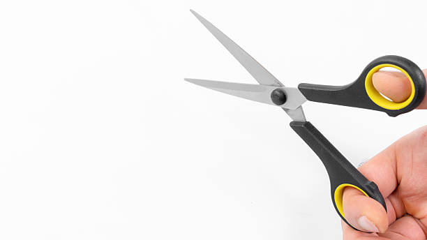 istock Close-up of a hand holding scissors ready for cutting tasks in a bright workspace environment 2214840088