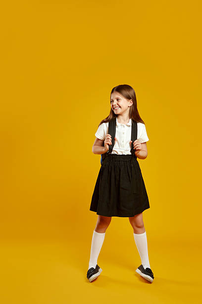 istock Cheerful young girl with backpack looking away while standing against vibrant yellow background 2214841437