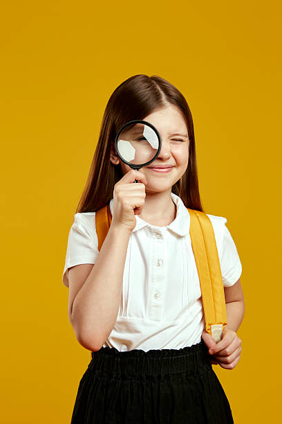 istock Curious young girl with magnifying glass exploring and learning in a playful school environment 2214842161