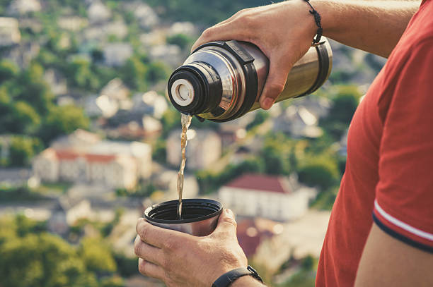istock Traveler pouring tea from thermos cup 2214842776