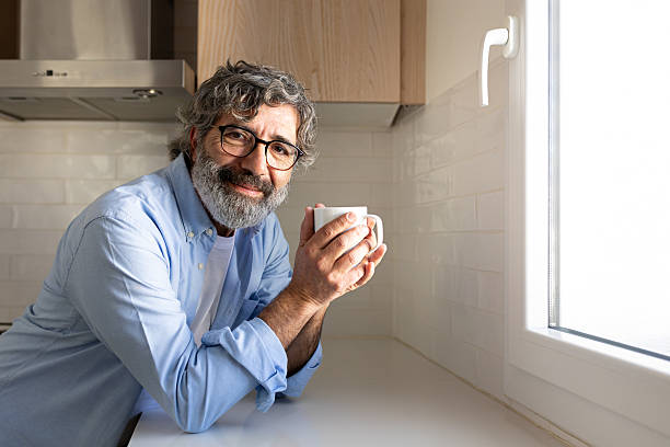 istock Smiling mature man enjoying a cup of coffee in his modern kitchen 2214843601