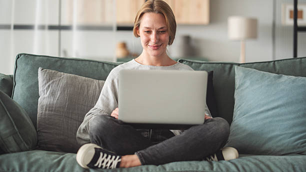 istock Woman sitting on sofa and using laptop at living room 2214844322