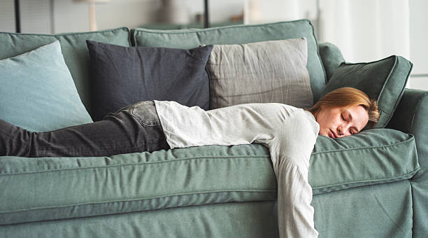 istock Exhausted young woman resting at home on couch 2214844349