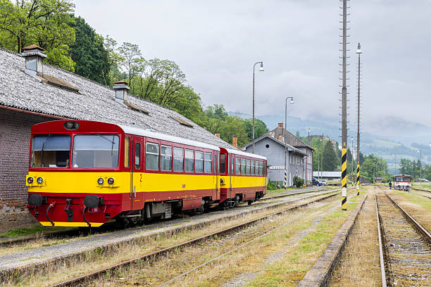 Red and yellow diesel railcar waiting at station platform on cloudy day