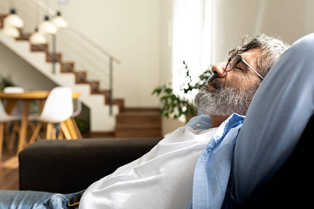 istock Senior man relaxing on sofa at home: enjoying peaceful retirement 2214848380