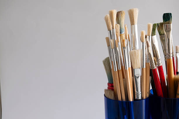 istock Oil paint brushes of various sizes in a blue glass container 2214849381