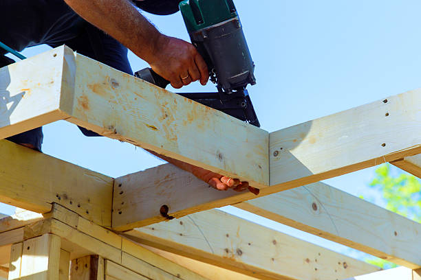 istock Skilled worker uses nail gun on wooden beams in a construction project under clear blue sky 2214850382