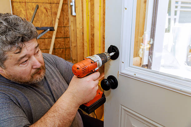 istock Man installing a door handle using a power drill in a wooden interior setting during daylight 2214850445