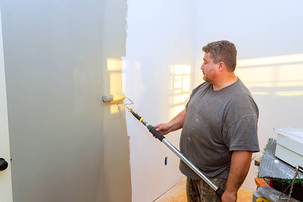 istock Man painting a wall with a roller in a room during daylight hours 2214850472