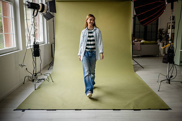 istock Young woman confidently walks on set during a studio photo shoot featuring creative lighting and modern backdrop 2214854227