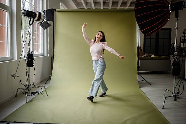 istock Young woman joyfully posing in a photo studio with creative lighting and a vibrant backdrop during a fashion photoshoot session 2214854947