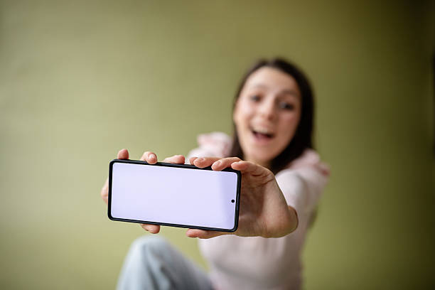 istock Young woman joyfully showcasing smartphone in a creative studio environment 2214855150