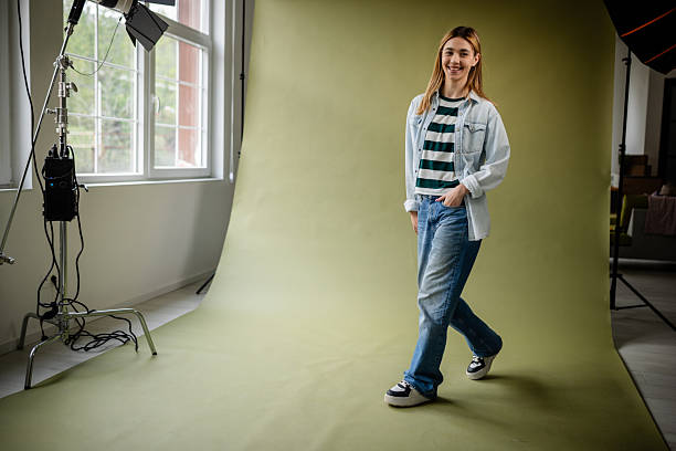 istock Young woman poses confidently in a studio while enjoying a fashion photo shoot on a green backdrop 2214856445