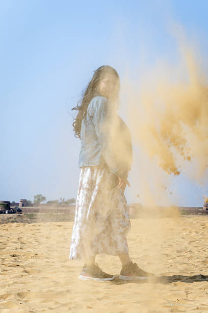 istock girl standing behind sand dust at bright day light 2214859848