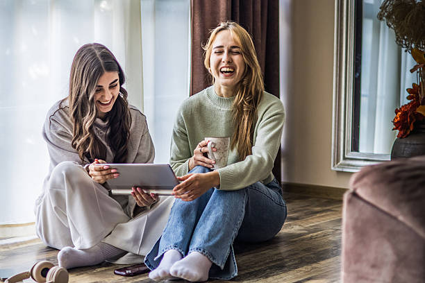 istock Connecting through technology. Two beautiful, smiling young women enjoying watching social media on digital tablet at home. Relaxing moment of friendship and bonding. 2214860190