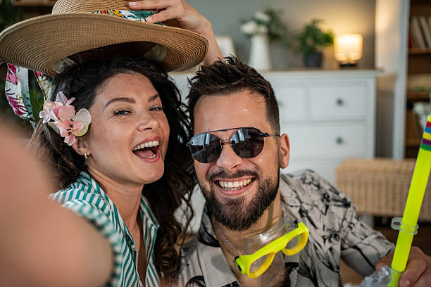 istock Young couple taking a selfie with summer accessories indoors 2214861371