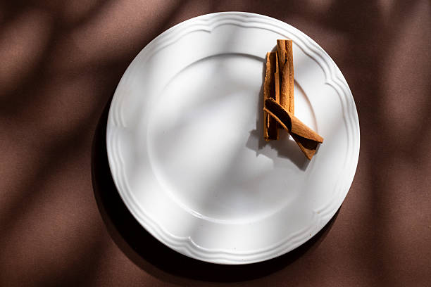 White ceramic dessert plates with cinnamon on brown background. Food concept with space for text