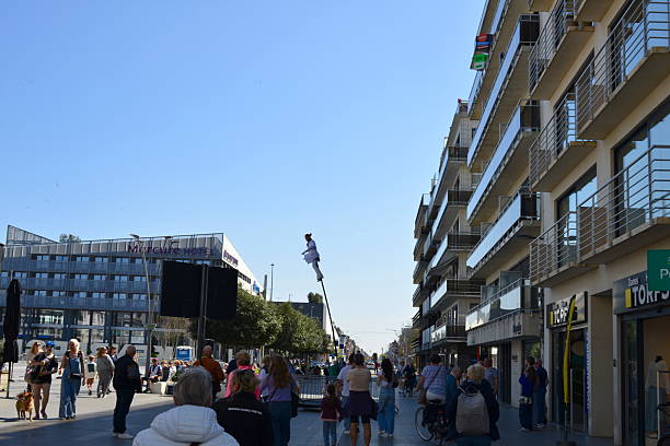 Blankenberge, West-Flanders, Belgium - April 12, 2025: tourists look in amazement at a man in a white suit swinging back and forth on a tall white flexible pole