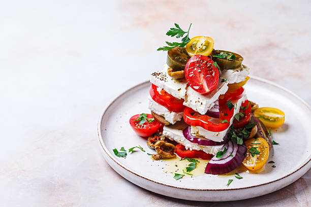 Greek salad stack with feta cheese, tomatoes, red onions and olives.
