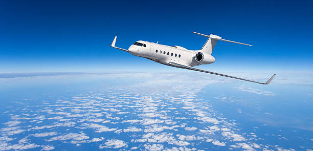 White private jet flying above clouds in blue sky