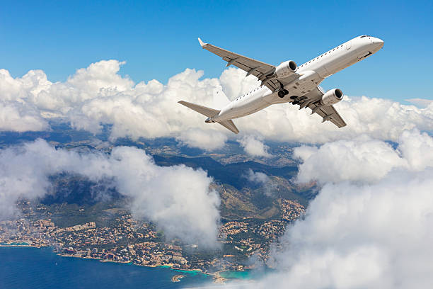 istock White passenger airplane flying above clouds and coastline 2214870072