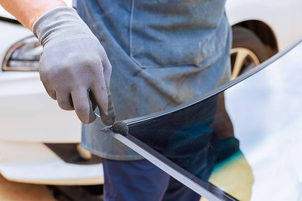 istock Professional technician installs adhesive for windshield replacement in auto service shop 2214870790