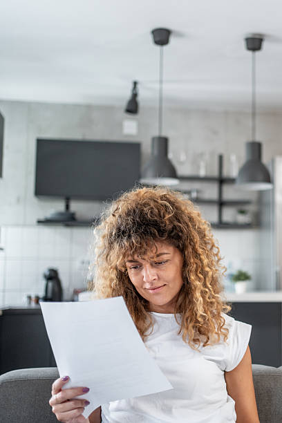 istock Woman reading documents at home in her living room 2214871322