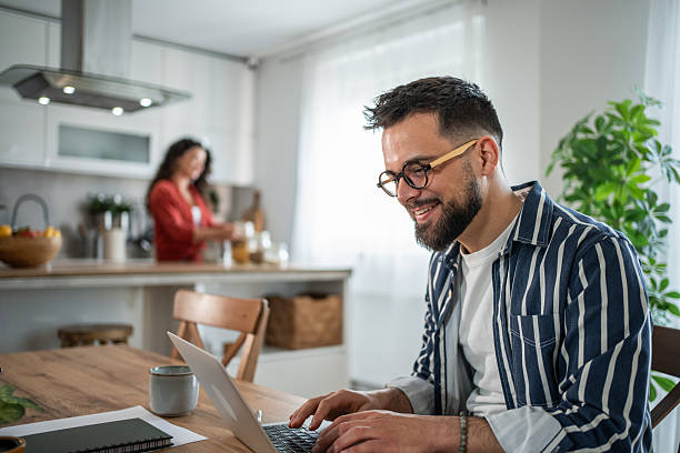 istock Young man working from home while wife prepares lunch 2214872346