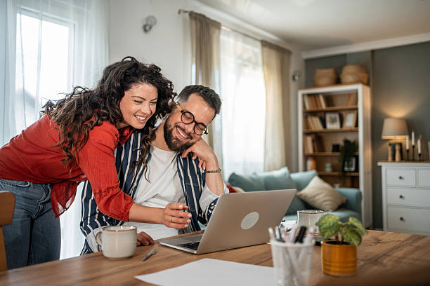 istock Happy couple working from home on a laptop and smiling 2214872411