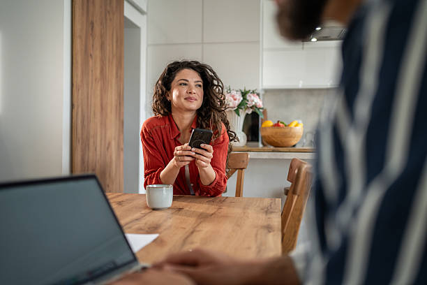 istock Woman using smartphone and dreaming at home while man is working on laptop 2214872429