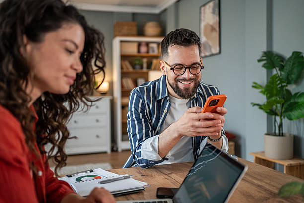 istock Young businessman using phone while working with his female colleague at home 2214872478