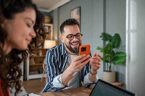istock Young businessman laughing while video chatting on his phone at home 2214872482
