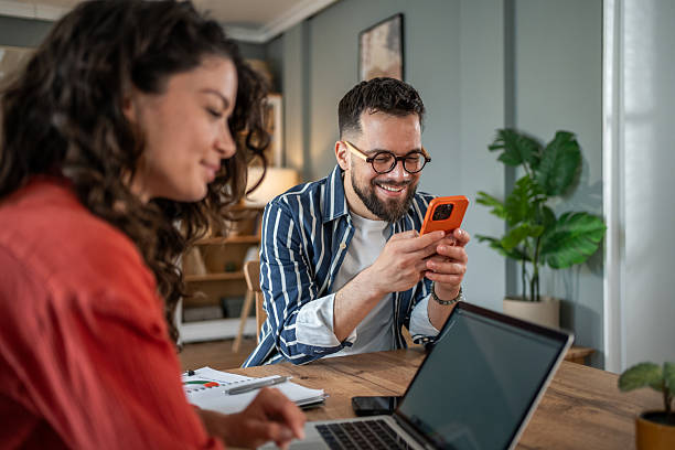 istock Young professionals working from home smiling and using mobile phone and laptop 2214872486