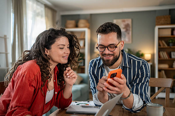 Couple working from home are looking at smartphone together
