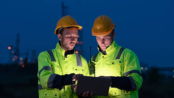 istock caucasian white engineers in safety uniforms and helmets using laptop and radio for site communication. Concept of teamwork, inspection, and operations at an industrial facility.Construction of Oil, Gas and Fuels Transport Pipeline,Pipe Manufacturing Fact 2214876189