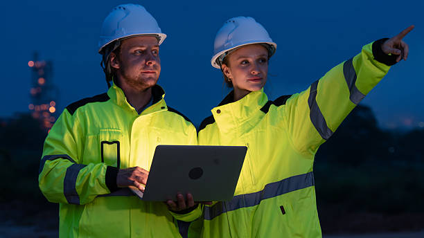 istock caucasian white engineers in safety uniforms and helmets using laptop and radio for site communication. Concept of teamwork, inspection, and operations at an industrial facility.Construction of Oil, Gas and Fuels Transport Pipeline,Pipe Manufacturing Fact 2214876195