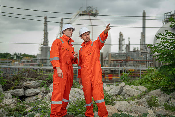 istock caucasian white engineers in safety uniforms and helmets using laptop and radio for site communication. Concept of teamwork, inspection, and operations at an industrial facility.Construction of Oil, Gas and Fuels Transport Pipeline,Pipe Manufacturing Fact 2214876211