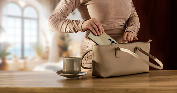 Female Hands Packing Purse at Desk – Workday Morning Routine. Copy space and business lifestyle, productivity, work from home, or daily routines concept.