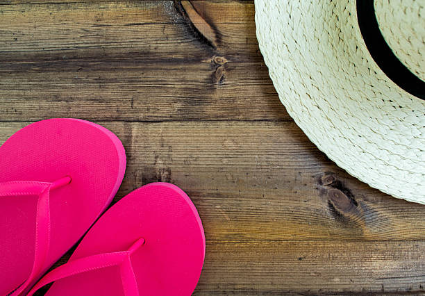 Summer vacation, flatlay. Hat and flip flops on a dark wooden background. Background for advertising.
