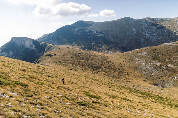 Woman hiker enjoying every step of amazing landscapes during her climb to the top of high altitude mountain.