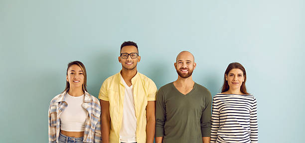 istock Diverse group of happy young people standing in row against blue studio background 2214889145