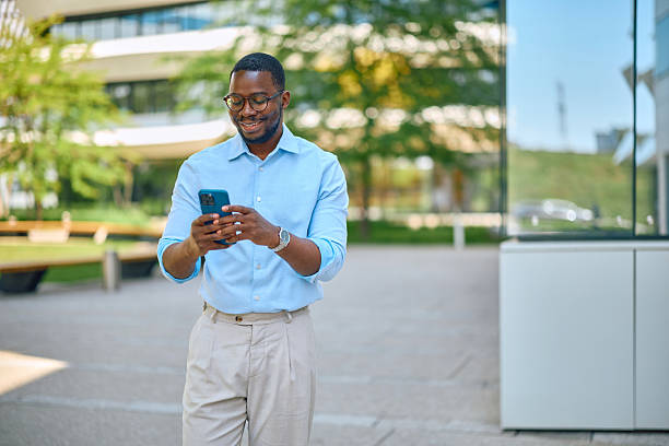 istock Smiling businessman using smartphone while walking near office buildings 2214889168